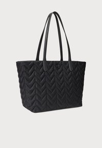 Crna torba za nošenje preko ramena s rebrastim uzorkom u obliku slova V, s dva čvrsta držača i logotipom na prednjoj strani. Izrađena od izdržljive tkanine.