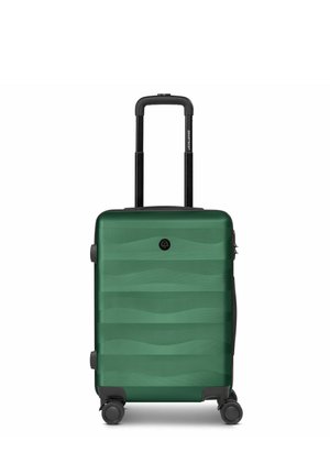 Maleta rígida verde con asa telescópica y cuatro ruedas giratorias, de pie sobre un fondo blanco.