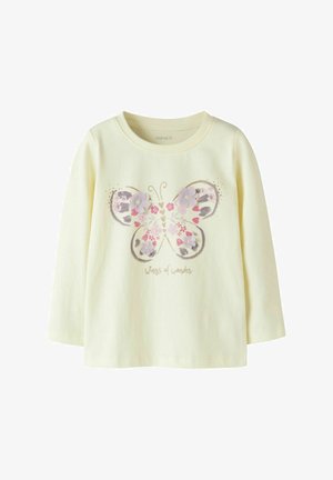 Camiseta infantil de manga larga color crema con un gran diseño de mariposa decorada con flores rosas y moradas y el texto "alas de maravilla" debajo.