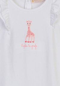 Camicia di cotone bianca con una grafica di una giraffa rosa con macchie rosse e il testo "Sophie la girafe" in rosa chiaro, accentuata da ruche.