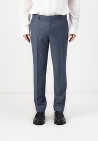 Blaue karierte Hose mit geradem Schnitt, flachem Frontbereich und Gürtelschlaufen, kombiniert mit schwarzen Schuhen und einem weißen Hemd mit Knöpfen.