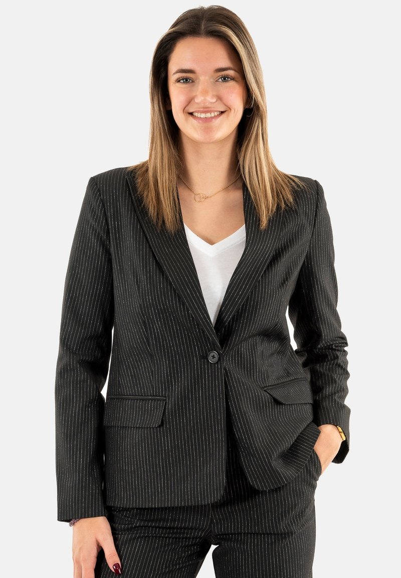 Blazer negro de rayas con un corte ajustado, cierre de un solo botón y dos bolsillos frontales, combinado con una camisa blanca de cuello en V.