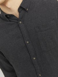 Camisa de botones de color gris oscuro en tejido texturizado, con un bolsillo en el pecho y botones marrones, con un diseño de cuello clásico.