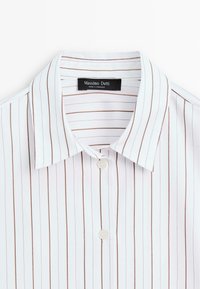Weißes Hemd mit dünnen vertikalen braunen und schwarzen Streifen und einem spitzen Kragen, Markenlabel "Massimo Dutti" im Nacken.