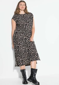 Midi-mekko leopardikuvioinnilla, rento istuvuus, hihattomat cap-sleveet ja pyöreä kaula-aukko, yhdistetty mustiin paksupohjaisiin saappaisiin kontrastia varten.