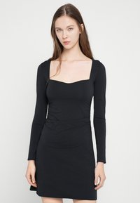 Melna kleita ar garām piedurknēm, kvadrātveida izgriezumu, piegulošu korseti un piegulošu tekstūru vidukļa līmenī, izgatavota no mīksta, elastīga materiāla.