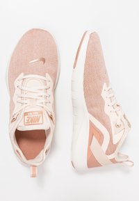 Nike sneakers in lichtroze mesh met een gestructureerde afwerking, voorzien van een witte zool en roségouden accenten. Veters en een trekkoordje inbegrepen.