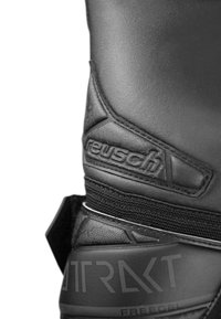 Schwarzer Torwarthandschuh aus strukturiertem Leder, verstärkter Handgelenkriemen und 'Reusch'-Logo. Mit gemusterten Akzenten und ergonomischer Form.