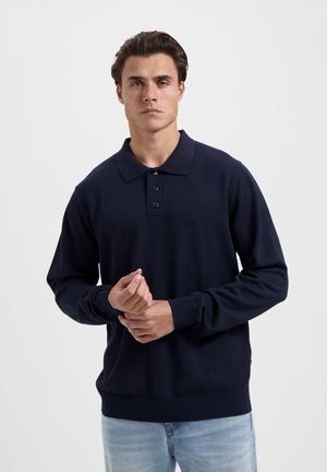 Marineblauwe polo met lange mouwen en een kraag, voorzien van een knoopsluiting en ribgebreide manchetten. Gemaakt van gebreide stof, heeft het een relaxte pasvorm.