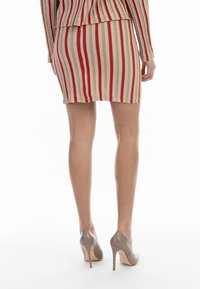 Rochie tricotată cu dungi verticale roșii și bej; siluetă ajustată. Purtați cu pantofi cu toc înalt gri deschis, cu vârf ascuțit și toc stiletto.