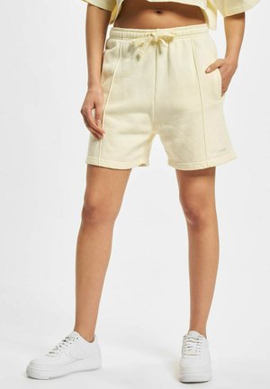 Light yellow cotton shorts with an elastic waistband and drawstring, featuring side pockets and a small logo on the leg.