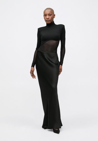 Rochie neagră cu un corset transparent cu mâneci lungi ajustate și o fustă fluidă din satin. Designul are un guler înalt și o tranziție fără cusături între materiale.