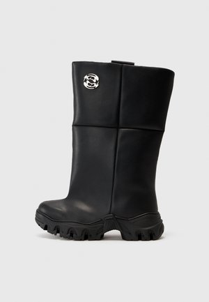 Schwarze kniehohe Stiefel mit einer glatten, glänzenden Oberfläche, ausgestattet mit einer strukturierten Gummisohle und einem silbernen Logo-Akzent an der Seite.
