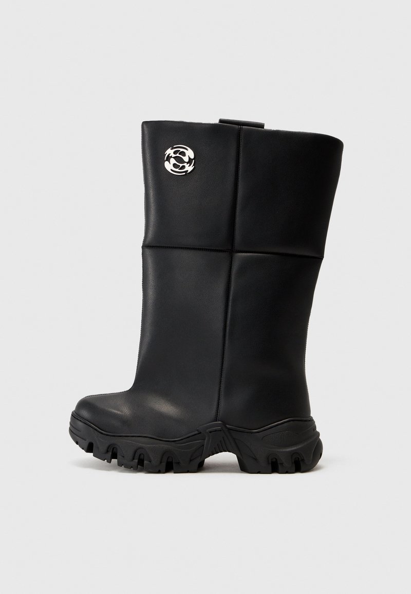 Svarta knähöga stövlar med en slät, glänsande yta, med en texturerad gummisula och en silverfärgad logotypaccent på sidan.