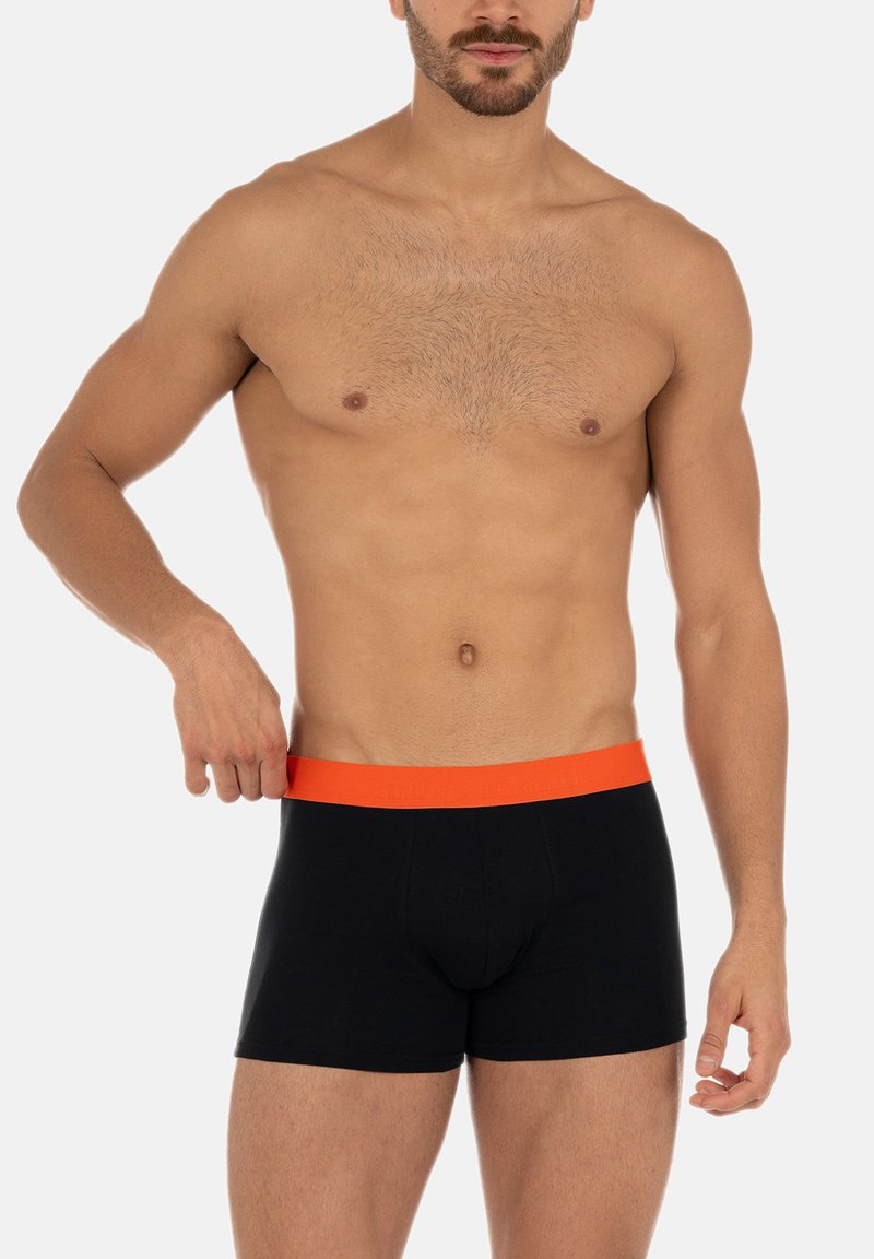 Svarta boxershorts med midjeband i orange elastik, med en åtsittande design och mjukt tyg, visade av en manlig modell.