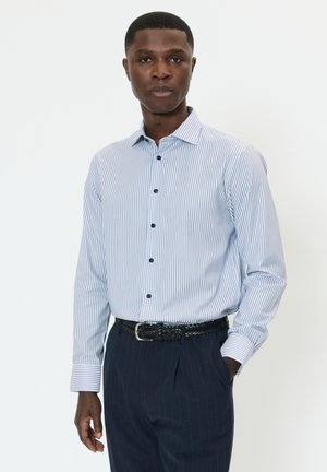 Helehallid ja valged triibulised pikkade varrukatega särk koos terava kraega, nööpidega ees ning tumelilla triibulised püksid, millele lisandub must kootud vöö.