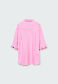 Camisa rosa de botones con cuello, mangas enrolladas y detalle de yugo en la parte posterior, hecha de una tela ligera y texturizada.