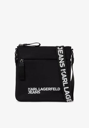 Svart nylontverttveske med glidelås. Har et trykt logo og en kontraststrop med tekst. Glatt tekstur og rektangulær form.