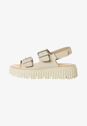Beige platform sandals feature two adjustable buckles, open toe design, and a textured ridged sole, with a slingback for secure fit.