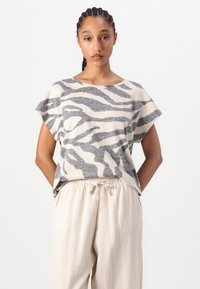 Haut à manches courtes rayé gris et crème, coupe décontractée, tissu doux, encolure arrondie. Associé avec un pantalon beige clair à cordon de serrage.