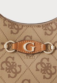 Bolso de tela con patrón en tonos marrones que presenta un acento de cuero marrón con un logotipo dorado de "G" y herrajes en tono dorado. Detalle de superficie texturizada visible.