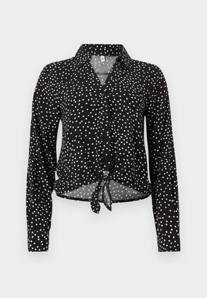 Chemise noire à manches longues avec boutons, motifs à pois blancs, col et lien à nouer à l'ourlet avant.