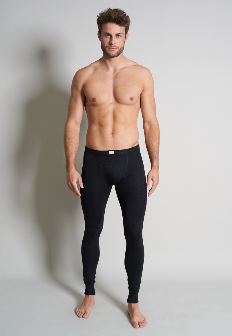 Black thermal leggings with a fitted design, stretchy material, and a snug waistband. Smooth texture and full-length coverage to the ankles.