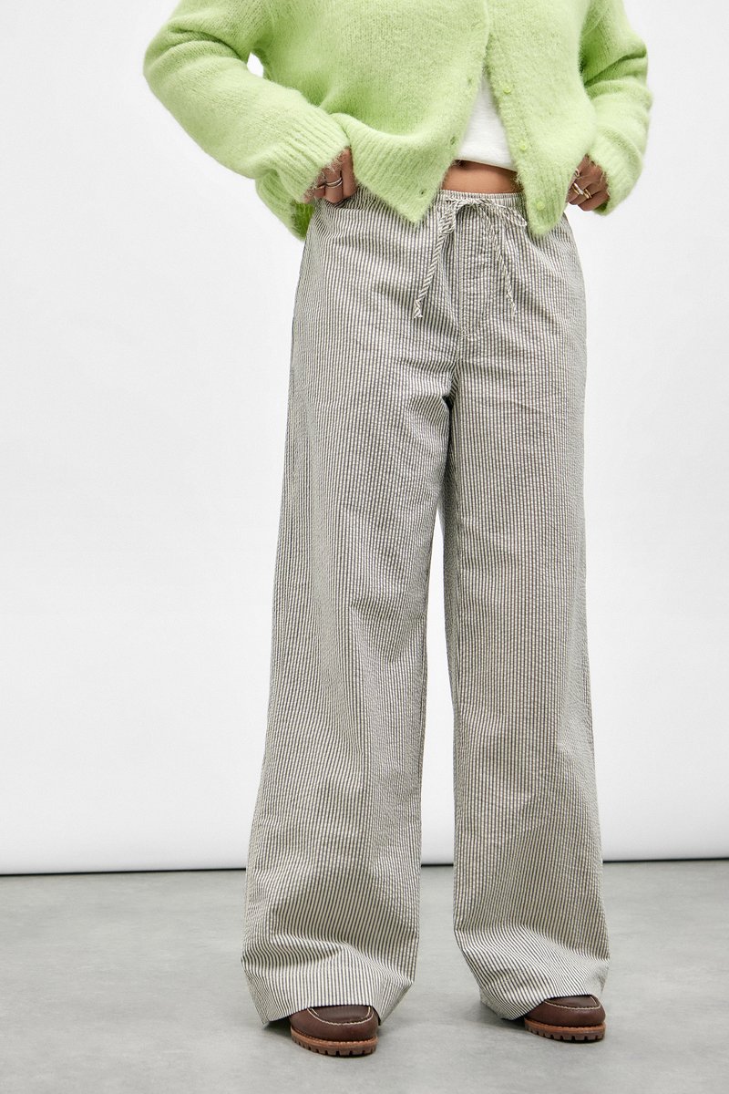 Pantalons à taille haute et jambes larges en rayures verticales grises et blanches. Dotés d'une taille à cordon de serrage et d'un tissu doux et texturé avec une coupe décontractée.