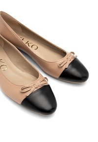Des ballerines en cuir beige clair avec un embout en cuir verni noir. Présentent de petits nœuds à l'avant et une doublure intérieure douce.