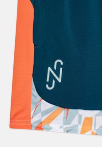 Camisa deportiva con un cuerpo texturizado en teal, mangas naranjas y un patrón geométrico multicolor en el dobladillo. Incluye un logo en azul claro.
