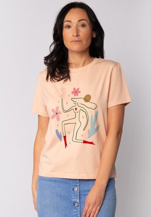 T-shirt en coton pêche avec un design graphique coloré représentant une figure dansante, des fleurs et des formes abstraites. Manches courtes, col rond.