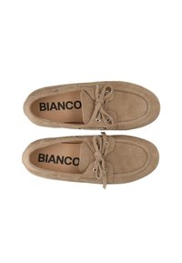 Vaalean beige-suede loaferit, joissa on pyöreä kärki ja nauhoitussuunnittelu. Varustettu hopeisilla reikillä ja teksturoidulla pinnalla. Sisällä näkyy "BIANCO"-logo.