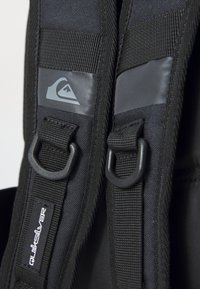 Schwarze Nylonriemen mit Kunststoffbeschlägen und grauen Logoakzenten. Verfügt über einen strukturierten Stoff und verstärkte Nähte für Haltbarkeit.