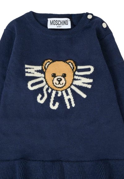 Maglione blu navy lavorato a maglia con colletto rotondo, decorato con una grafica di un orso e la scritta "Moschino" in bianco. Include due bottoni decorativi sulla spalla.
