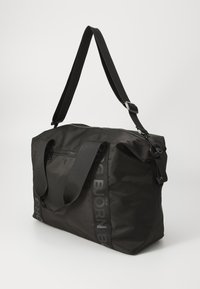 Svart duffelbag laget av teksturert nylon med glidelås, to korte håndtak og en lang justerbar stropp. Har logo-detalj på siden.