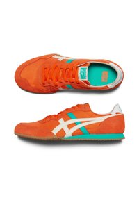 Sneakers in suede arancione con accenti bianchi e acquamarina, dotati di un design con lacci e suola in gomma texturizzata. Branding notevole sulla linguetta.