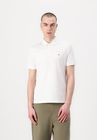 Witte poloshirt met een ritskraag, gemaakt van gladde katoen. Heeft korte mouwen en een klein logo op de linkerborst. Casual fit.