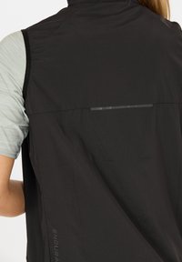 Schwarze, leichte Radweste aus strukturiertem Ripstop-Gewebe. Verfügt über einen reflektierenden Streifen auf der Rückseite und ein Logo an der Seite.