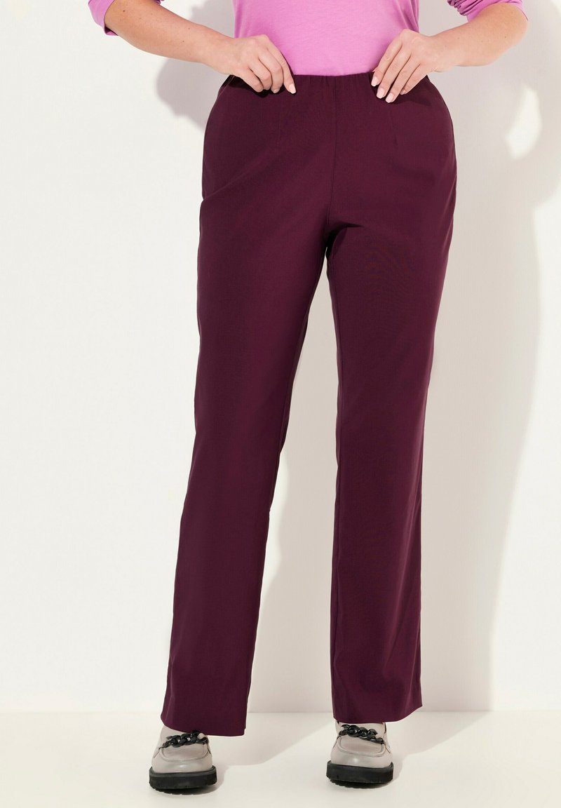 Bordeauxkleurige broek met een elastische tailleband, rechte pijpdesign en een soepele stofstructuur. Draagt met zilveren schoenen.
