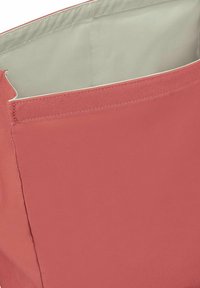 Interior de una bolsa de tela de color coral con forro claro, que presenta una forma redondeada y costuras resistentes. Sin hardware visible ni patrones.