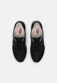 Svarta sneakers med överdelar i mocka och mesh, rund tå, snörningsdesign och vit sula. Interiören har en röd och vit logotyp.