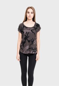 Camo print short-sleeve top in black and gray, round neckline, relaxed fit, paired with black leggings. Smooth, lightweight fabric.