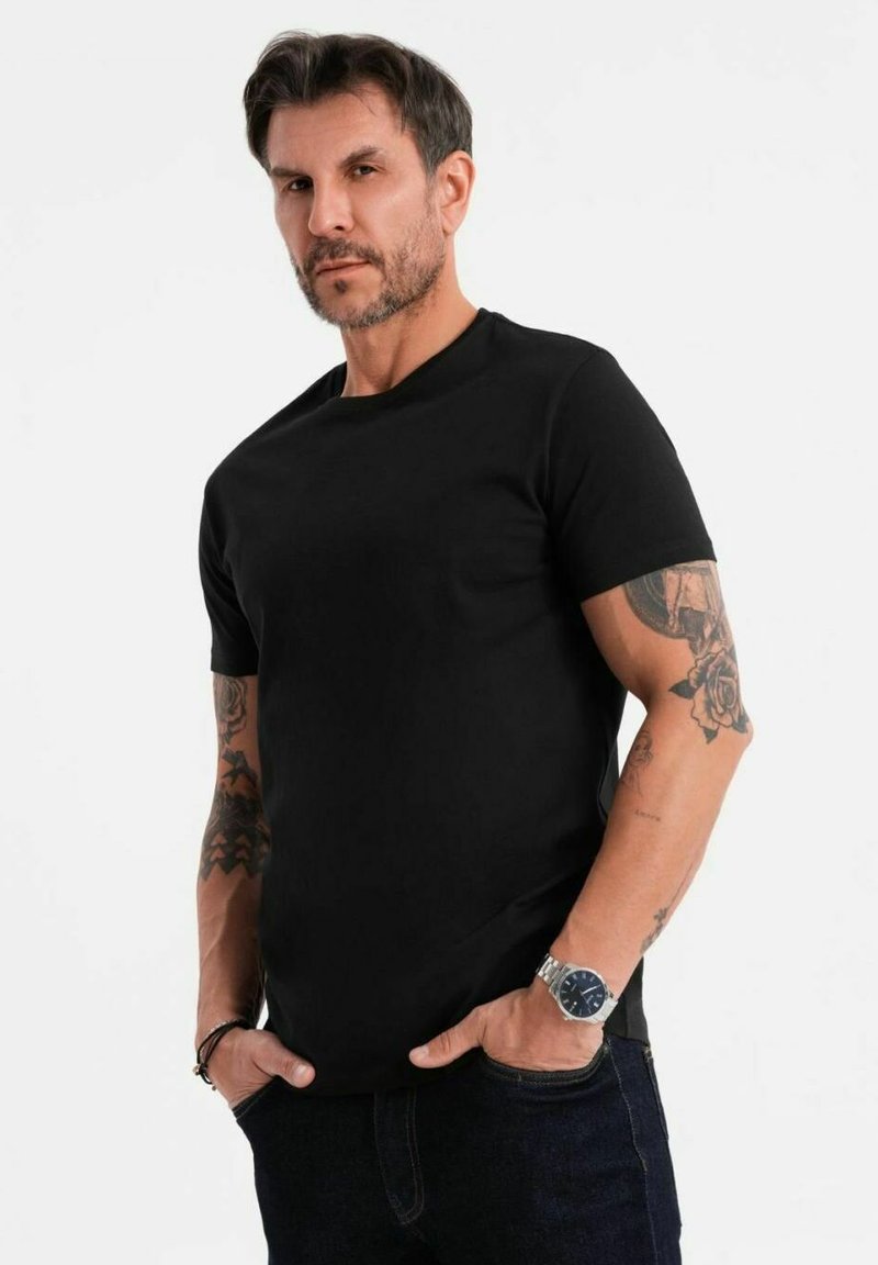 Musta lyhythihainen t-paita klassisessa leikkauksessa, valmistettu sileästä puuvillasta, jossa on pyöreä kaula-auko ja ei näkyviä kuvioita tai yksityiskohtia.