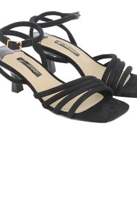 Sandalias de tacón de ante negro con múltiples tiras entrelazadas y punta cuadrada. Con un tacón corto tipo bloque y forro interior beige.