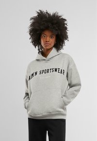 Szürke kapucnis pulóver elülső kenguruzsebbel, fekete "AIM'N SPORTSWEAR" logóval és "EST. 2013" felirattal, kényelmes szabásban.