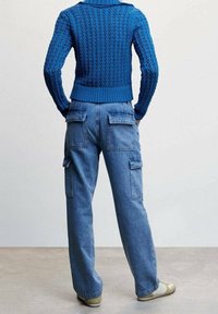 Blauer Strickpullover mit strukturierter Musterung, kombiniert mit geraden Jeans-Cargohosen mit mehreren Taschen.