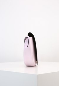 Růžová kožená kabelka s elegantní siluetou, kontrastními černými akcenty, zakřiveným vrškem a minimalistickým designem. Hladká textura, žádné viditelné kovové prvky.
