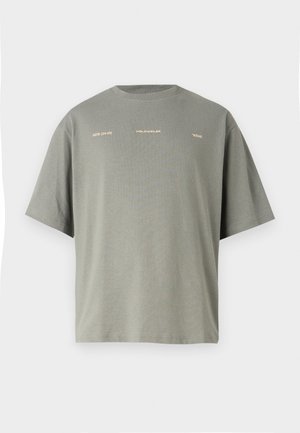 Nadmerné tričko s krátkym rukávom v olivovo zelenej farbe z bavlny. Na prednej strane má bielo-zlatý text, okrúhly výstrih a voľný strih.