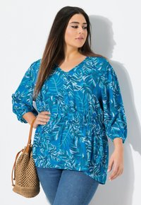 Blusa blu con scollatura a V e vita arricciata. Caratterizzata da un motivo a foglia in varie tonalità di blu e bianco. Maniche lunghe a palloncino.