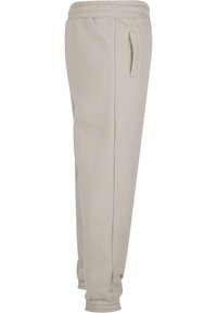 Light beige sweatpants made of soft fabric, featuring an elastic waistband, side pockets, and ribbed cuffs at the ankle.